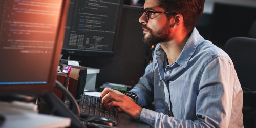 Male programmer working on new project. He working late at night at the office.