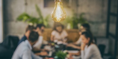Young business people are discussing together a new startup project. A glowing light bulb as a new idea.