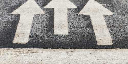 Zebra, pedestrian crossing with road marking. White arrows and stripes on a dark asphalt