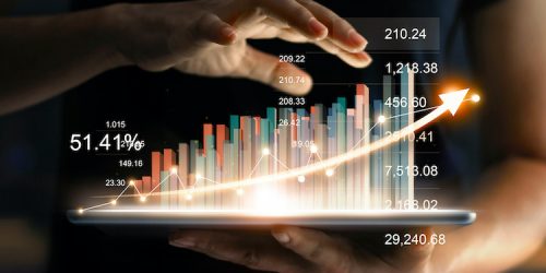 businessman holding tablet and showing a growing virtual hologram of statistics, graph and chart with arrow up on dark background. Stock market. Business growth, planing and strategy concept.